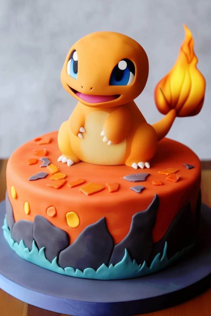 A vibrant cake with an orange topping features a detailed Charmander figure sitting on top. The cake is decorated with flame-like patterns and colorful geometric shapes, captured on a blue circular base.