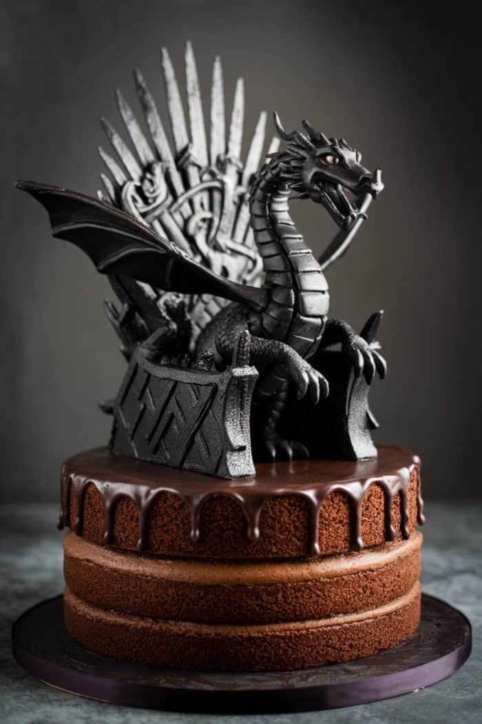 Chocolate cake with glossy icing, topped with a detailed sculpture of a dragon sitting on a throne made of swords, resembling a famous fictional throne. The background is a dark, muted color, emphasizing the cake's intricate design.