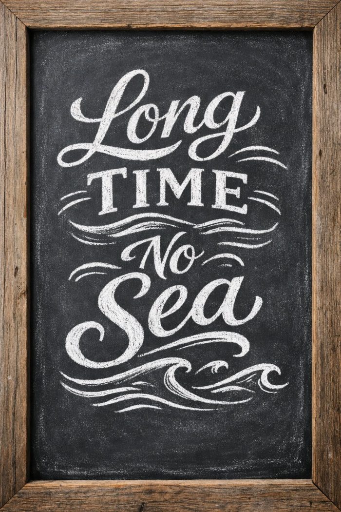 Chalkboard with decorative white lettering reading “Long Time No Sea,” surrounded by wave illustrations, framed in rustic wood.